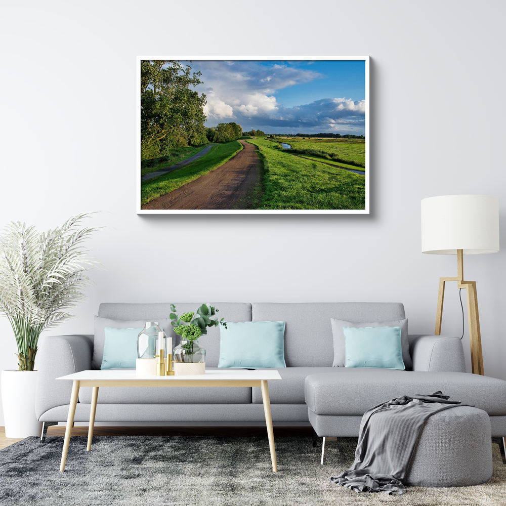 Acrylic landscape photo print in a white frame above a gray sofa in a bright living room