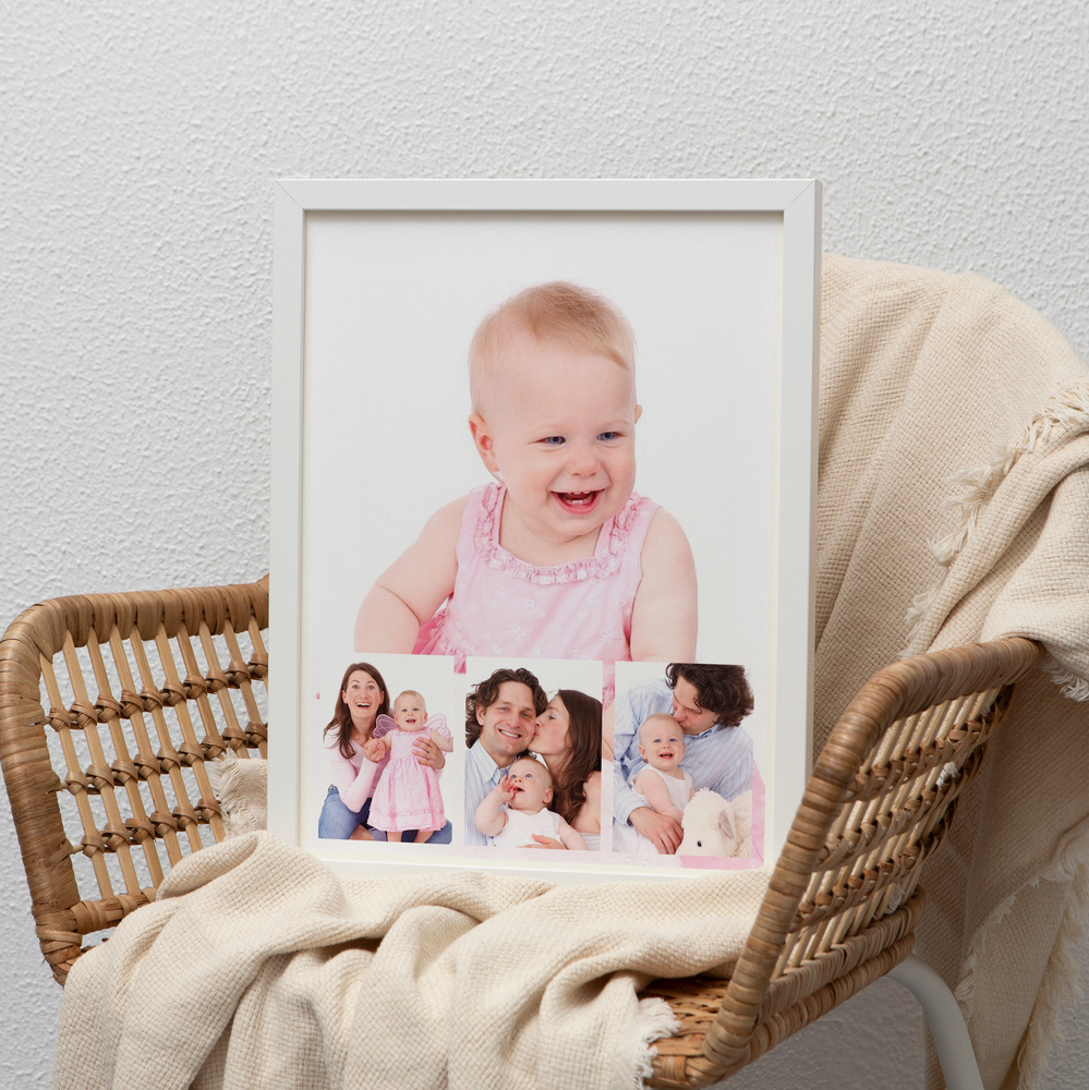 White-framed family photo collage with a child portrait resting on a wicker chair, a thoughtful photo gift for parents