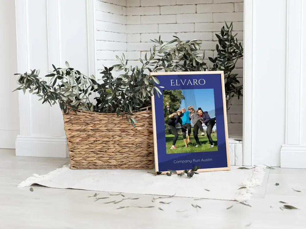 Framed company run photo poster with a navy background, on the floor beside a plant basket, a gift for coworkers