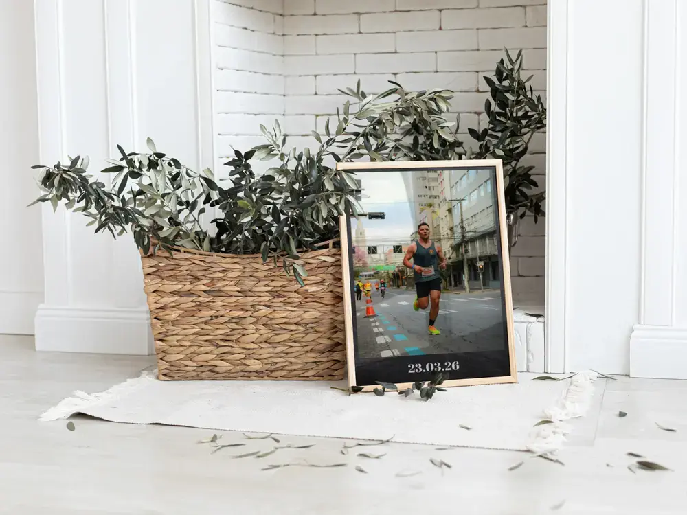 Wood-framed marathon photo print with a runner and date, resting beside a plant, a keepsake gift for a finisher