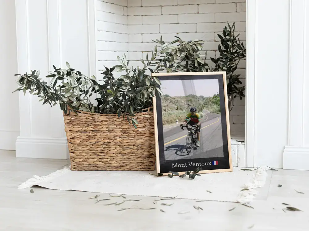 Framed road cycling photo with a location caption, on the floor beside a plant basket, a gift for cyclists