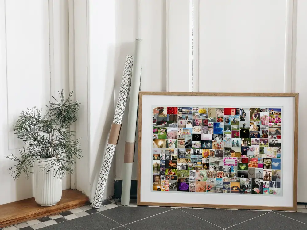 Wedding collage with many photos in varied sizes, in a natural wood frame on the floor beside a plant