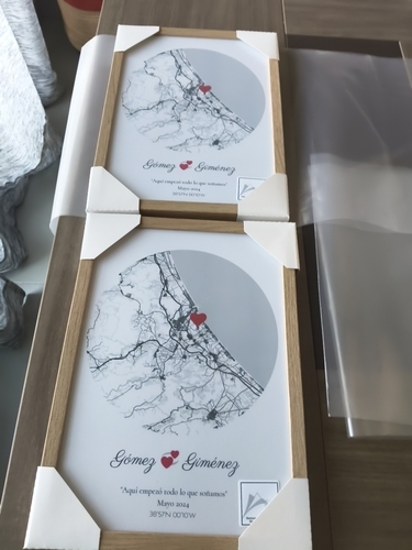 Two circular city map posters with heart markers in natural wood frames on a table, a romantic gift